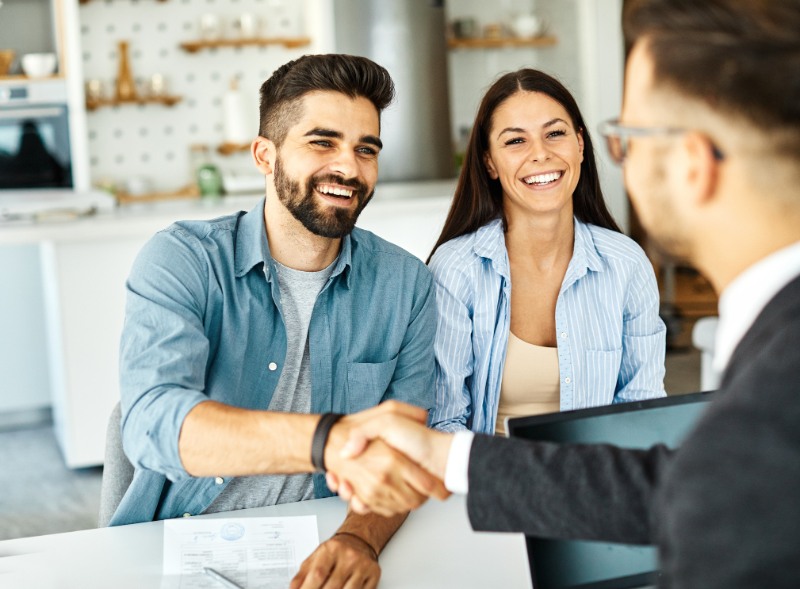 Young couple shaking hands deal contract